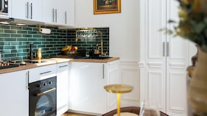 Une cuisine moderne avec des meubles blancs, un pare-feu vert et un coin repas aménagé pour prendre un repas.