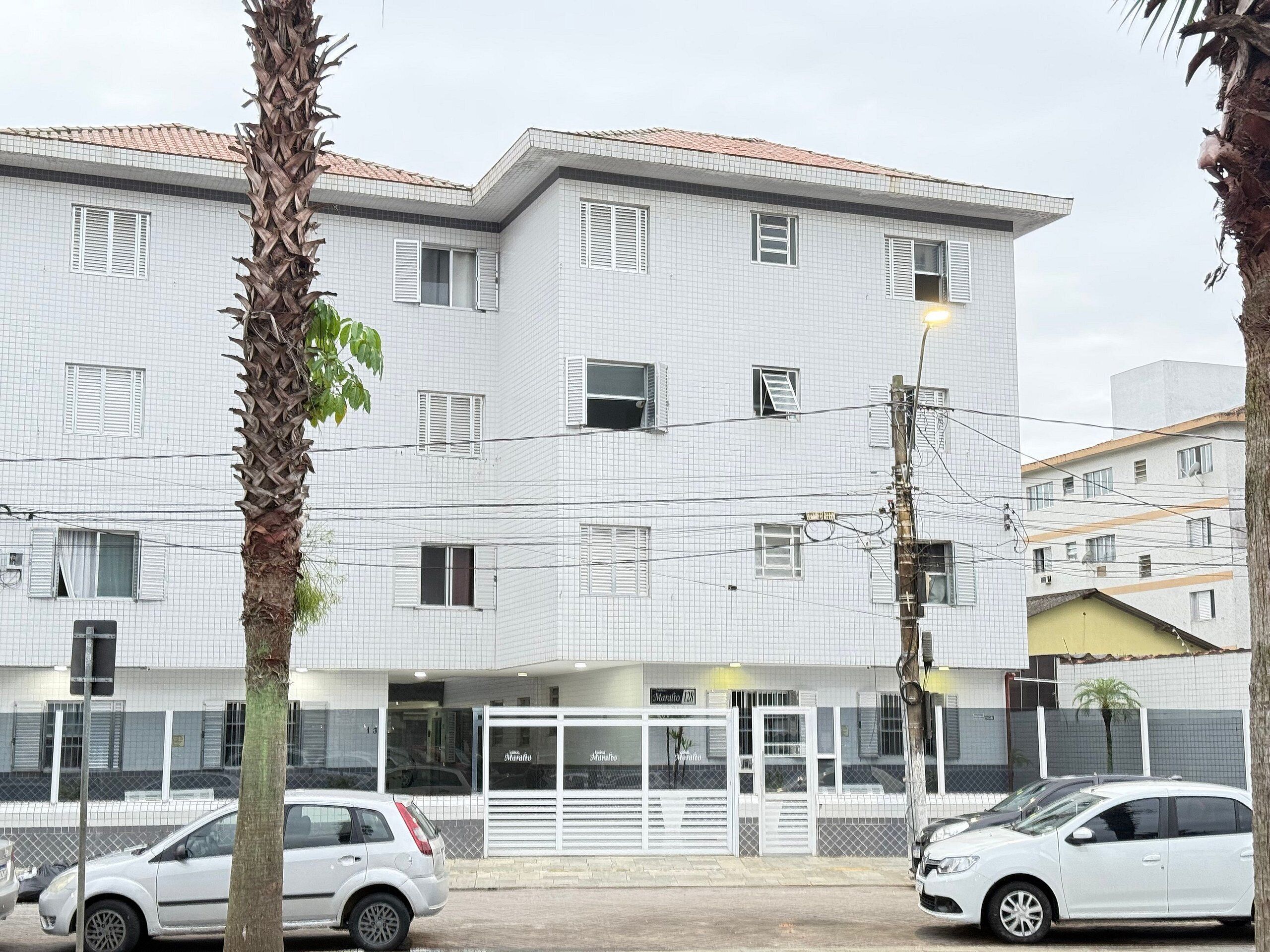 A multi-story building with a tiled facade, several windows with shutters, and a gated entrance.