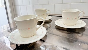 Tres tazas blancas de cerámica con diseños florales sobre una encimera de cocina.