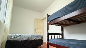 Una habitación con dos literas, un ventilador de techo y una puerta.
