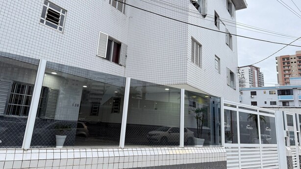 Un edificio con fachada de tejas, varias ventanas y acceso de vidrio.