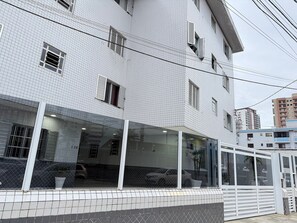 Un edificio con fachada de tejas, varias ventanas y acceso de vidrio.