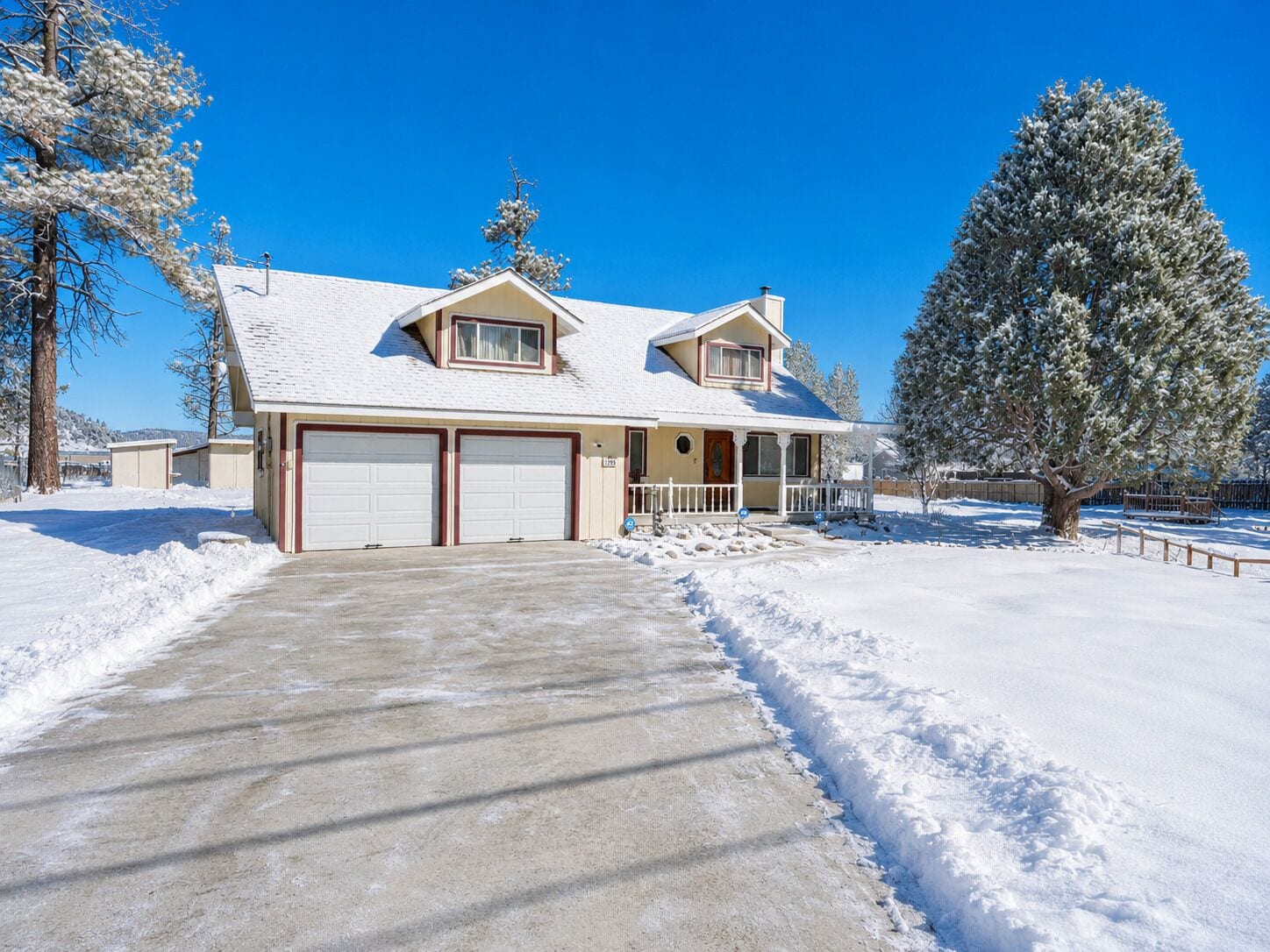 A two-story house with a garage, a covered porch, and a snow-covered landscape.