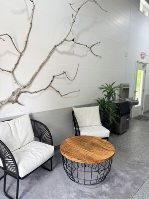 A modern lounge area with a sofa, chairs, a round table, and a decorative wall piece.