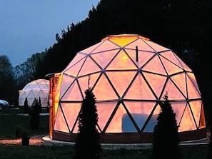 Eine geodätische Kuppel inmitten von Bäumen, mit einer zentralen Lichtquelle.