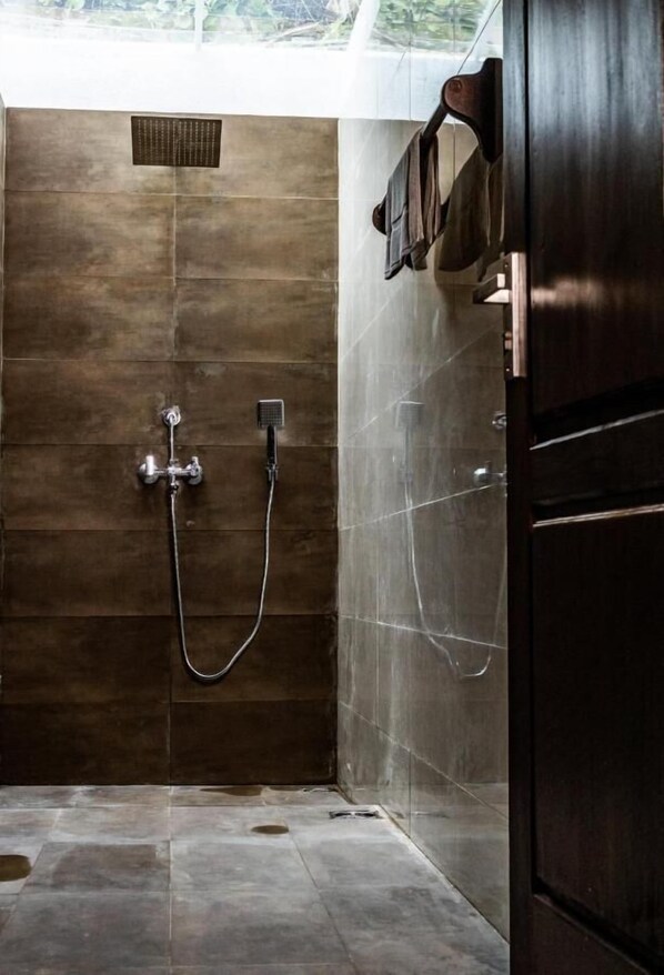 A shower area with a built-in wall-mounted showerhead and a handheld showerhead.