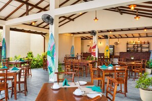 A restaurant with wooden tables and chairs, a bar area, and surfboards as decor. - Nature Surf Villas (Dikwella)