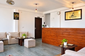 A hotel reception area with a wooden reception desk, a clock, and a framed logo on the wall. - Nature Surf Villas (Dikwella)