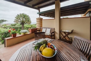 A wooden table with a fruit bowl, a bench, and a small table with a newspaper. - Welcome to Heaven in Stintino (Stintino)