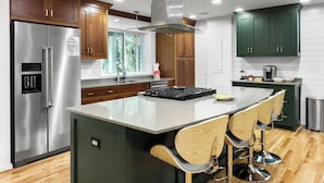Uma cozinha moderna com eletrodomésticos de aço inoxidável, armários de madeira e uma ilha central com banquetas.