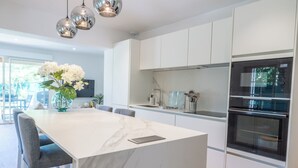 A modern kitchen with white cabinetry, a marble island, and stainless steel appliances. - Les Tamaris (SAINTE TERRE)