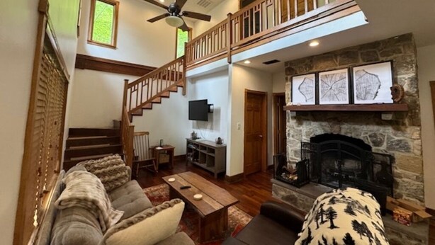 A spacious living room with a fireplace, a staircase to an upper level, and a television on the wall. - Tranquil Cardinal Hill Cabin- Perfect for Relaxation & Exploration. Pet Friendly (Sperryville)