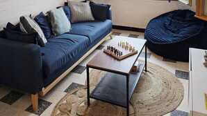 Uma sala de estar moderna com um sofá azul, uma mesa de centro de madeira e um tabuleiro de xadrez.