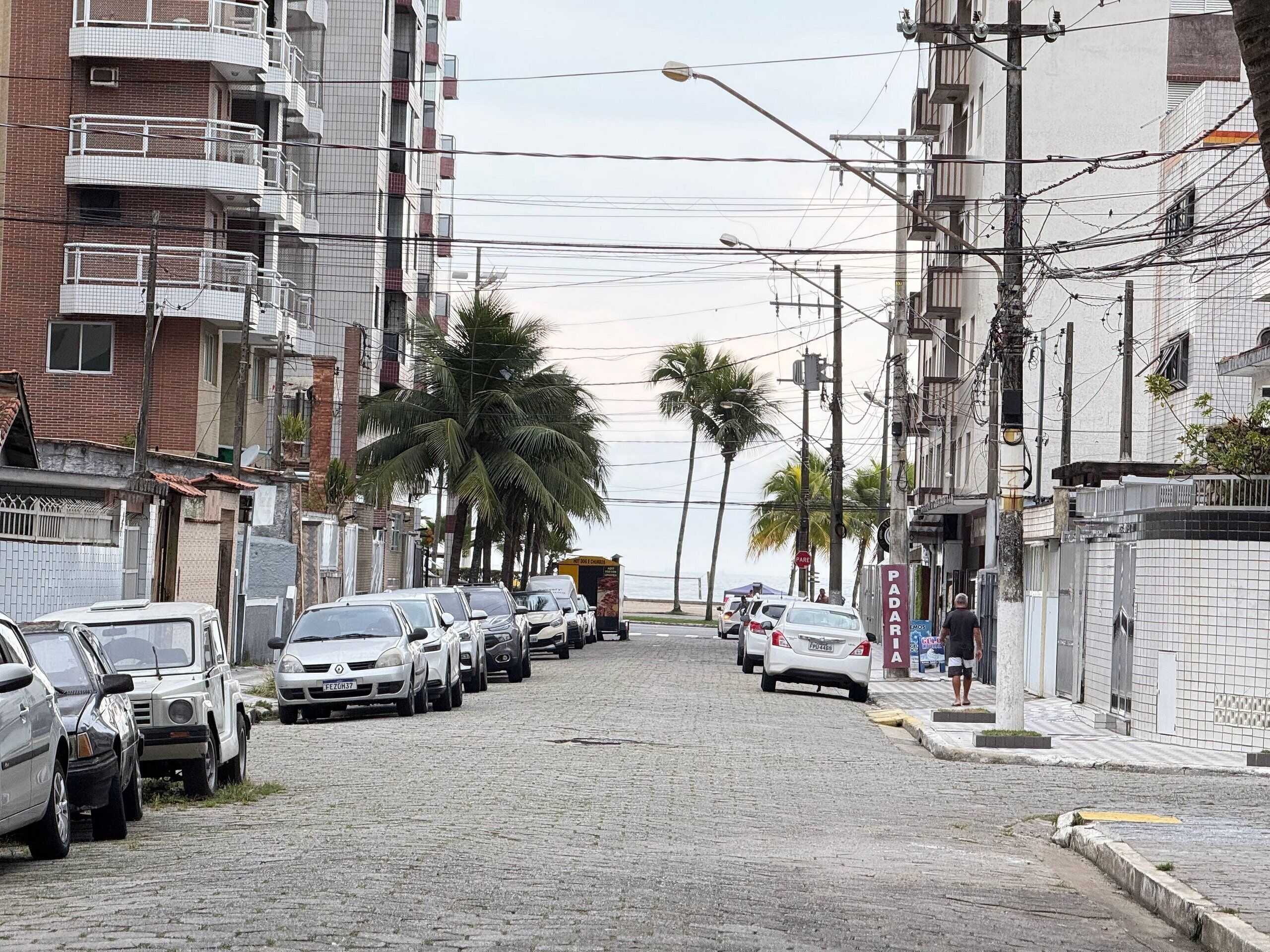 Une rue pavée bordée de voitures garées et d’immeubles à plusieurs étages.