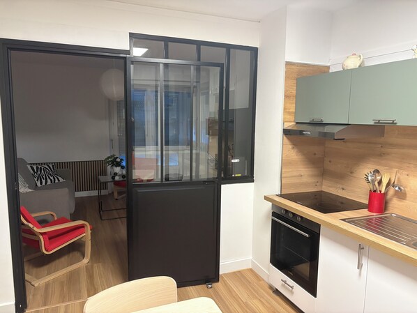 A modern kitchen with a built-in oven, a wooden countertop, and a red utensil holder.