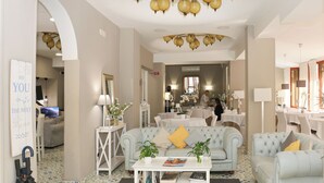 Een ruime woonkamer met een lichtblauwe bank, een witte salontafel en een decoratieve plafondlamp.