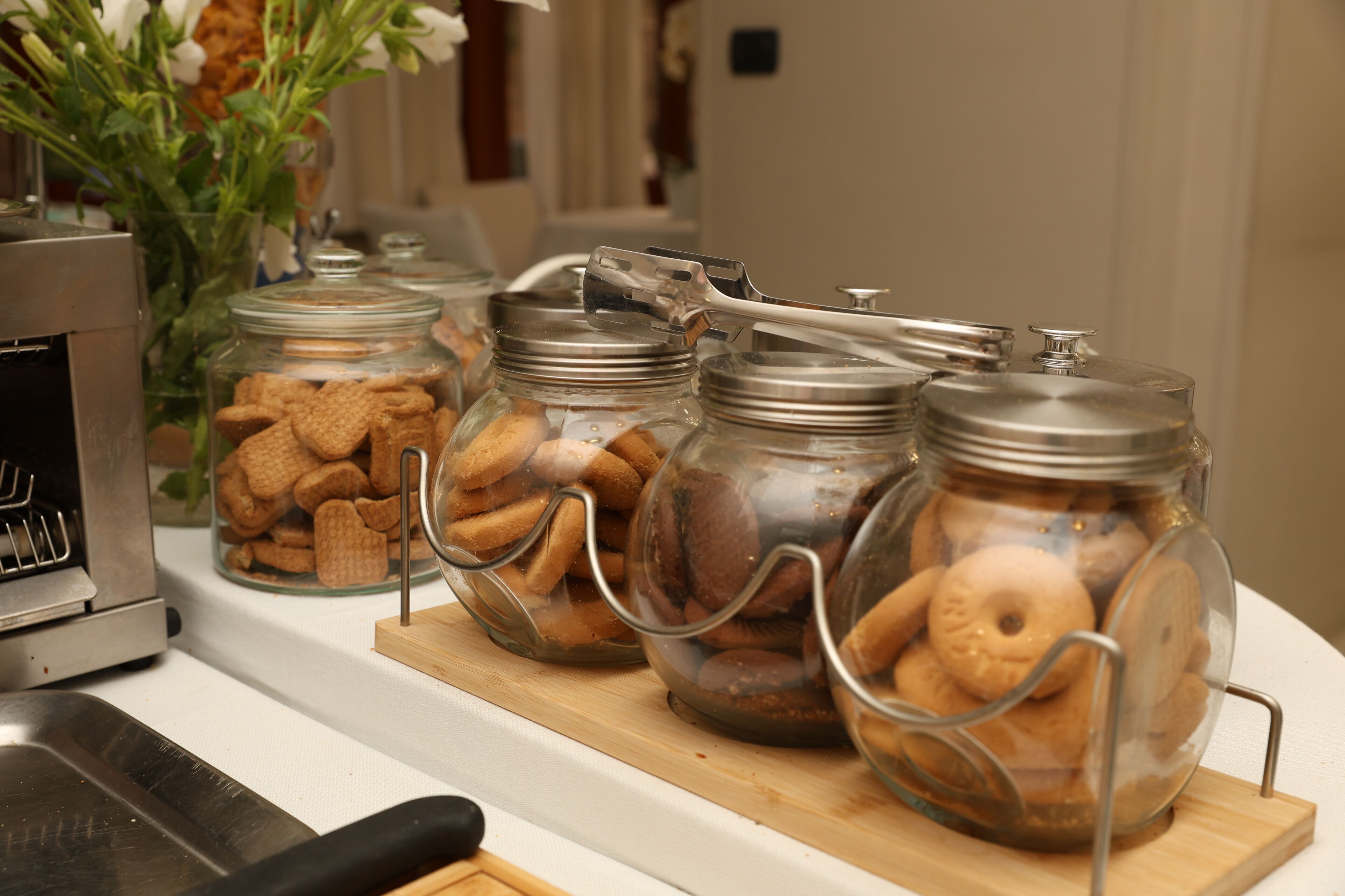 Glass jars with metal lids on a wooden board, containing cookies and biscuits.
