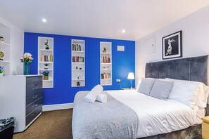 A bedroom with a bed, a dresser, and built-in shelving with books and decorative items.