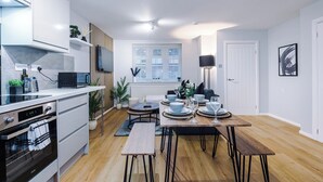 Eine moderne Küche mit Essbereich, ausgestattet mit Einbaugeräten, einem Esstisch für vier Personen und einem Fenster mit Jalousien.