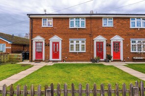 A two-story brick house with red doors and white window frames.