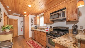Una cucina con mobili in legno, piani di lavoro in granito, un fornello e un forno a microonde.