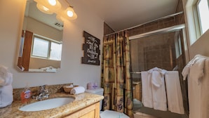 Un bagno con lavabo su piano in granito, un water bianco, una doccia con porta in vetro e una finestra che offre luce naturale.