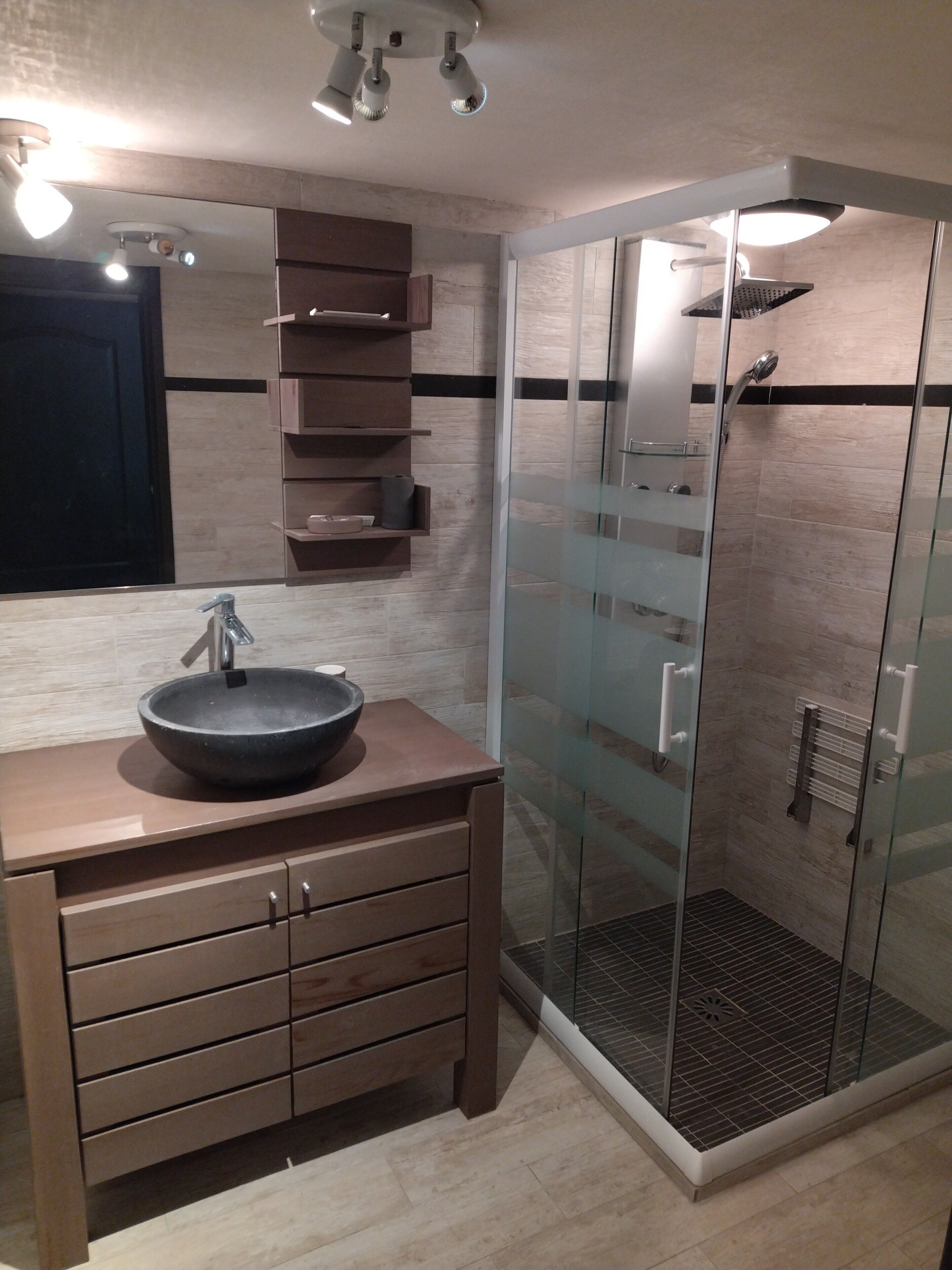 A modern bathroom with a large sink, a glass shower enclosure, and a wooden vanity.