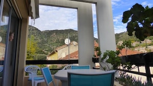Een balkon met een tafel en stoelen, met uitzicht op een bergachtig landschap.