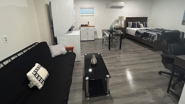 A compact living space with a kitchenette, a dining area, a sofa, and a bed.