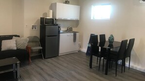 A compact living space with a kitchenette, a dining area with a table and chairs, and a sofa.