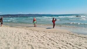 Une plage où l’on voit des gens se promener et nager dans l’eau.