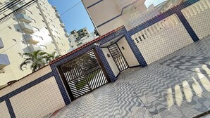 Un edificio de varios pisos con fachada de tejas y entrada protegida por una reja.