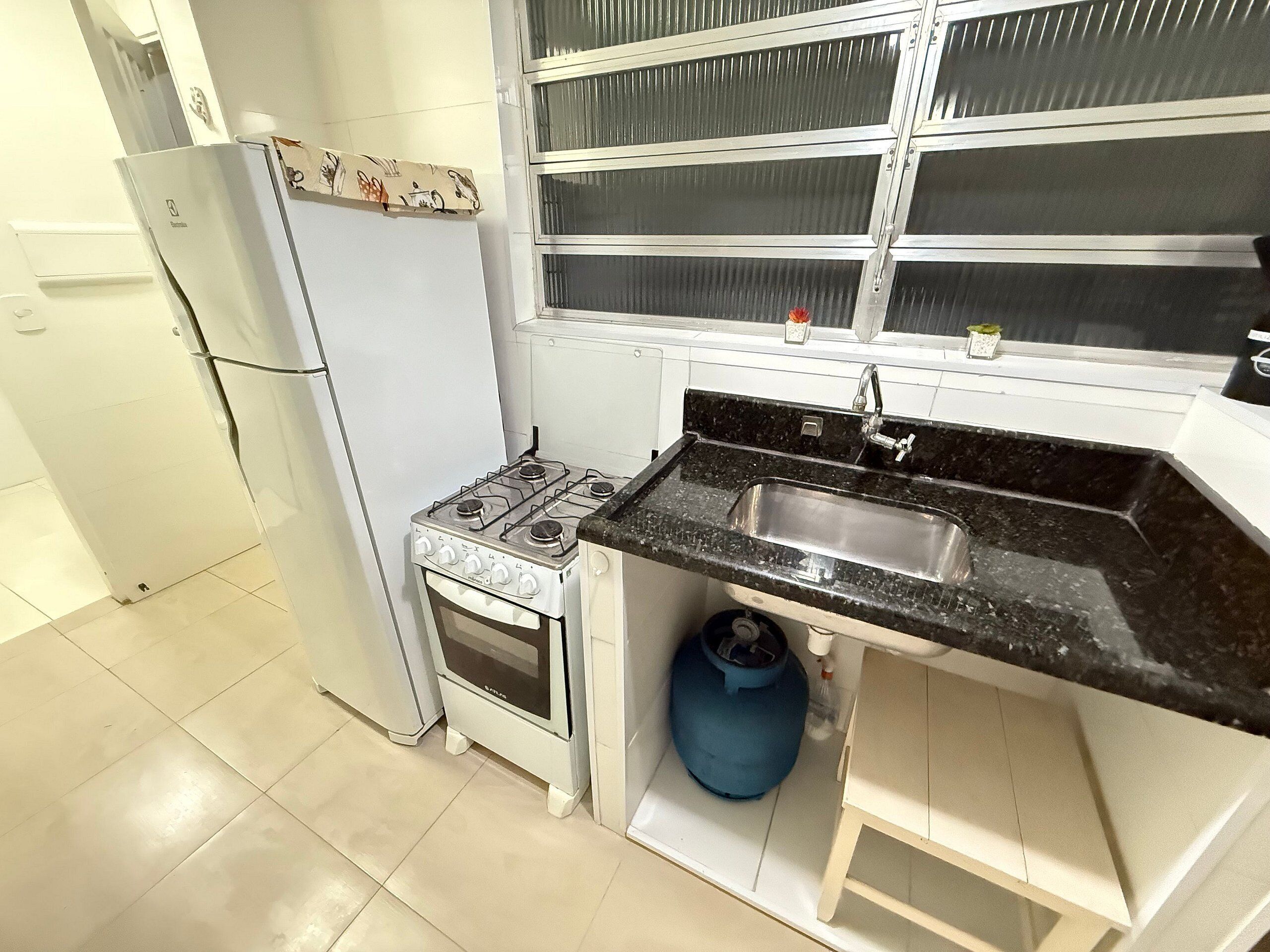 Uma cozinha compacta com fogão a gás, pia e geladeira.