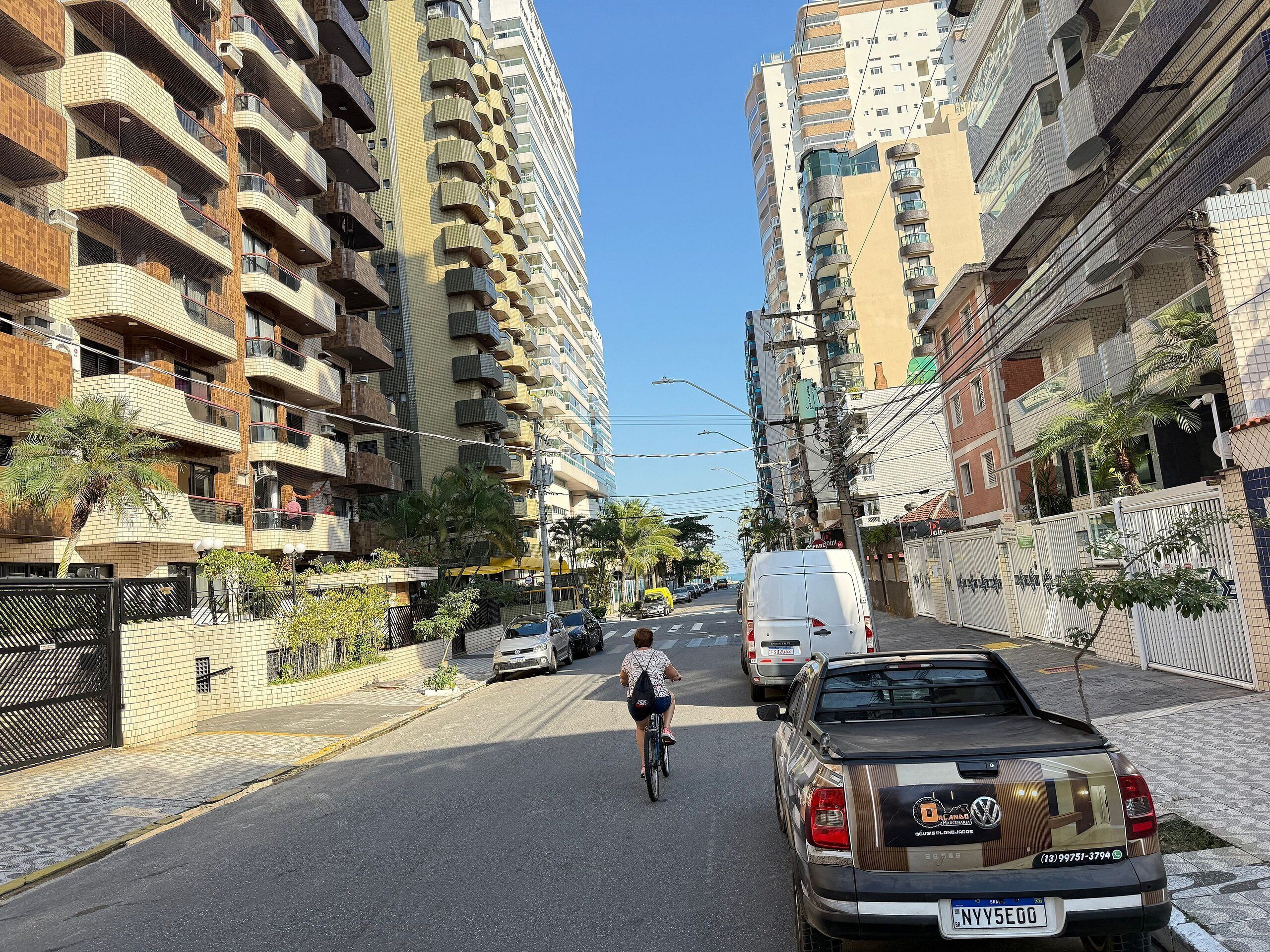 A street with a building featuring multiple balconies and a parked car.