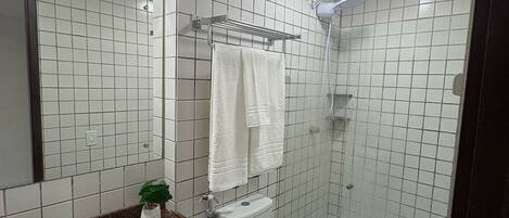 Un baño moderno con encimera de granito, un lavabo blanco, un inodoro y una ducha con mampara de vidrio.