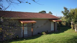 A single-story house with a red-tiled roof, a covered porch, and a well-maintained lawn. - Celeste Suites, in Vale dos Vinhedos with Bathtub and Colonial Breakfast (Vale dos Vinhedos)