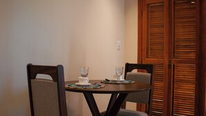 A dining area with a wooden table and chairs, a tiled floor, and a wooden door with shutters. - Celeste Suites, in Vale dos Vinhedos with Bathtub and Colonial Breakfast (Vale dos Vinhedos)