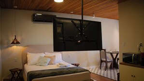 A bedroom with a bed, bedside table, lamp, and a TV mounted on the wall. - Celeste Suites, in Vale dos Vinhedos with Bathtub and Colonial Breakfast (Vale dos Vinhedos)