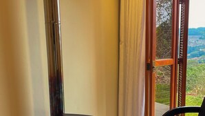 A room with a black wood-burning stove, a wicker basket, a chair, and a view through a glass door. - Celeste Suites, in Vale dos Vinhedos with Bathtub and Colonial Breakfast (Vale dos Vinhedos)