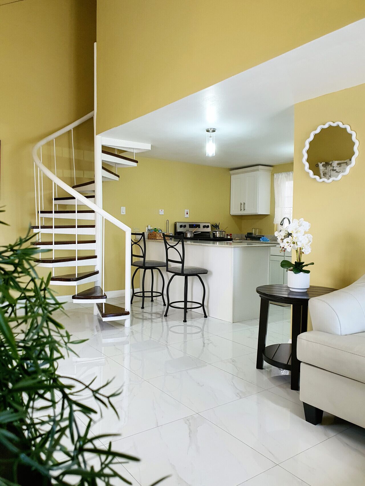 A modern kitchen with white cabinets, a central island, and two bar stools.