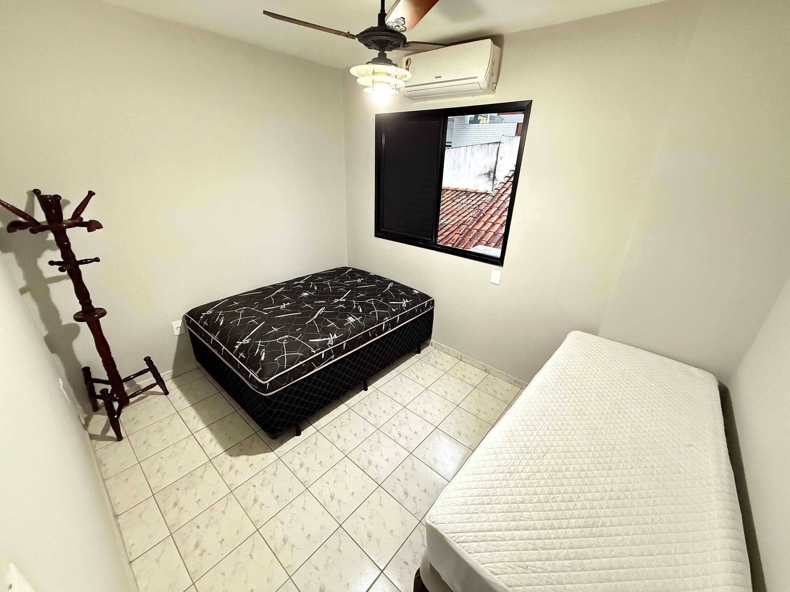 Una habitación pequeña y limpia con cama, perchero y ventilador de techo.