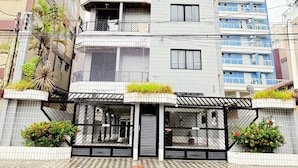 A multi-story building with a modern design, featuring balconies and a gated entrance. - Pé na Areia Canto do Forte VI (Praia Grande)