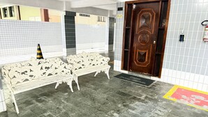 A lobby with a bench, a door, and tiled walls. - Pé na Areia Canto do Forte VI (Praia Grande)