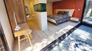 Un dormitorio moderno con cama, mesita de noche y vistas a través de un ventanal.