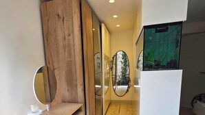Una habitación moderna con un escritorio de madera, un espejo redondo y un amplio ventanal con vistas a zonas verdes.