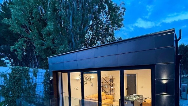 Una casa moderna con un salón acristalado, un comedor y una cocina a la vista.