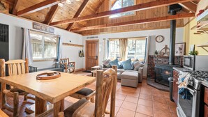 Un interior rústico con una mesa de comedor de madera, una chimenea y una zona de cocina.
