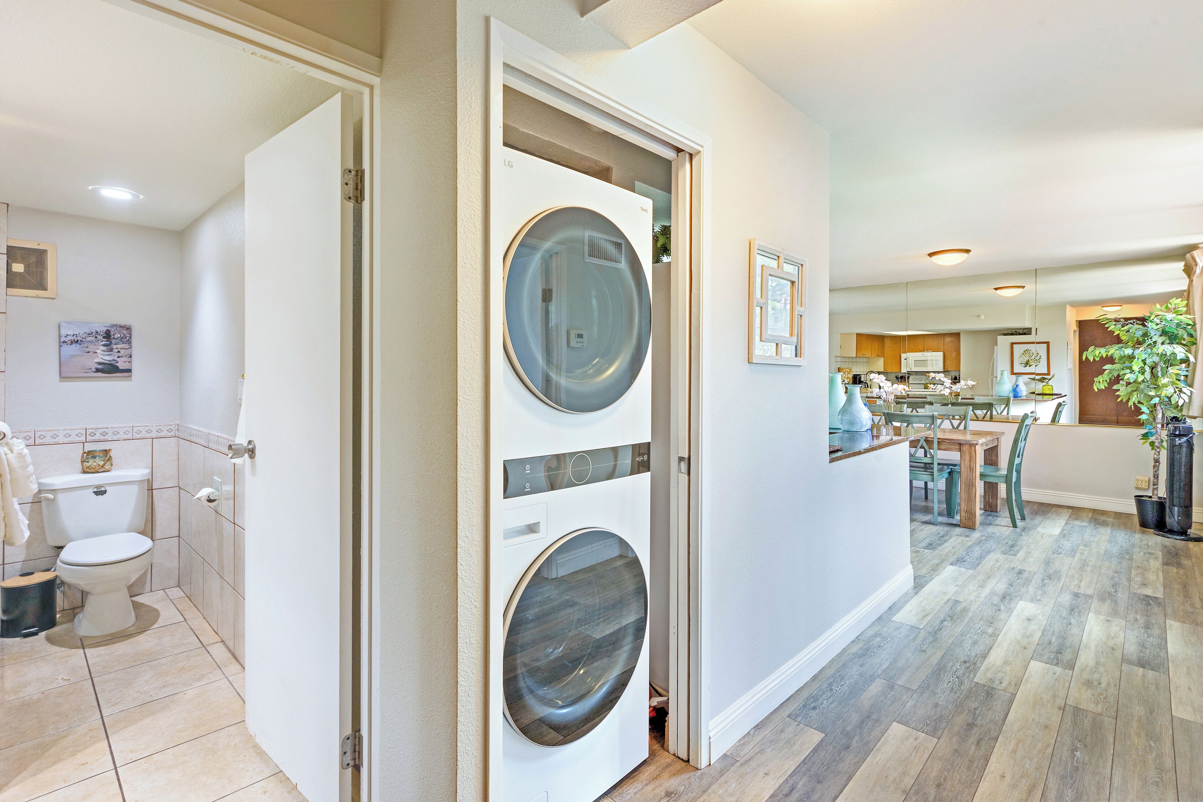 A laundry room with two front-loading washing machines and a toilet.