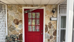 A red door with a 'WELCOME' sign, a stone wall, a bench, and a doormat. - “30 Day or more rental” Private RAINBOW RIVER access! (Dunnellon)