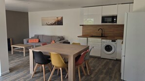 Un apartamento moderno con zona de comedor, sofá, cocina y lavadora.